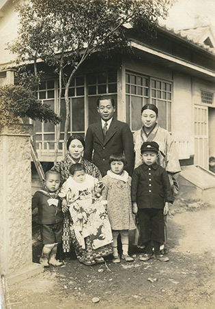 佐々木さんの子どもの頃の住まいの前で撮影された白黒の家族写真